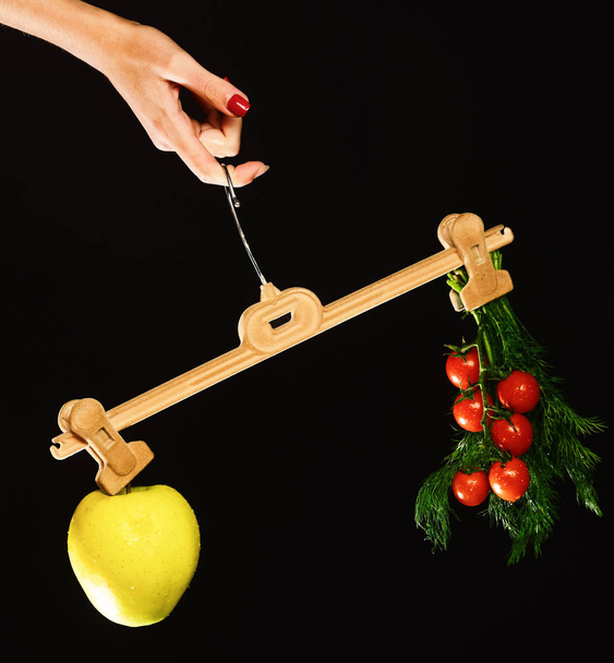 Female hand holds hanger with fruit and vegetables on tips - Foto, afbeelding