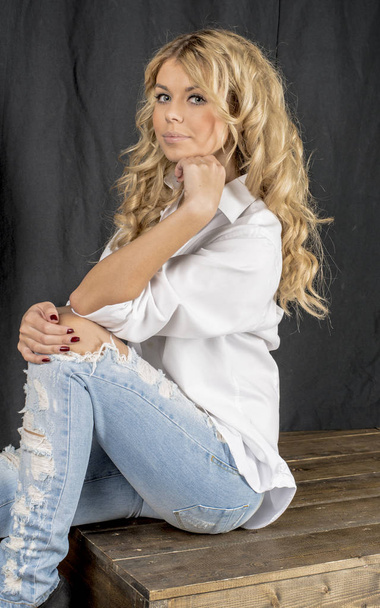Young beautiful girl blonde in a white shirt and jeans with gaps - Foto, Bild