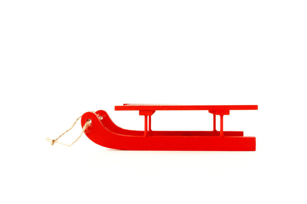 Trineo de madera en vibrante color rojo y con cuerda de yute aislada sobre fondo blanco
. - Foto, imagen
