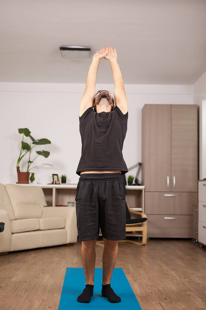 Aantrekkelijke man met baard doen terug stretch staande omhoog - Foto, afbeelding
