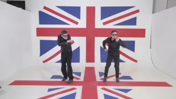 zwei energische süße Männer in schwarzen Motorradjacken und Sonnenbrillen tanzen - Filmmaterial, Video