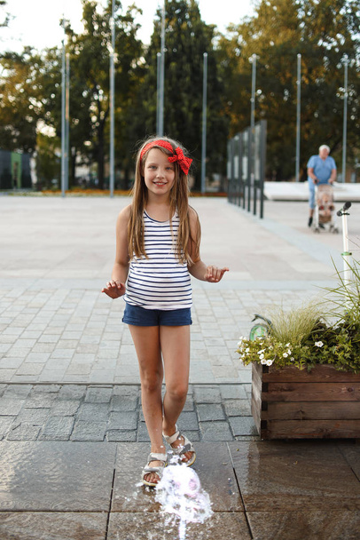 linda niña divirtiéndose mientras juega en charco en la calle
  - Foto, imagen