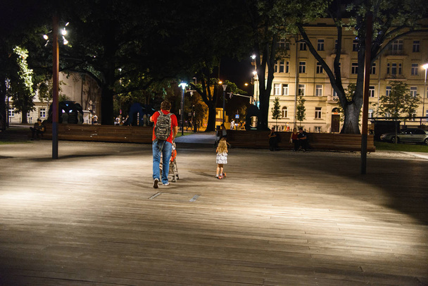 father with daughter and son walking at square in midnight city park  - 写真・画像
