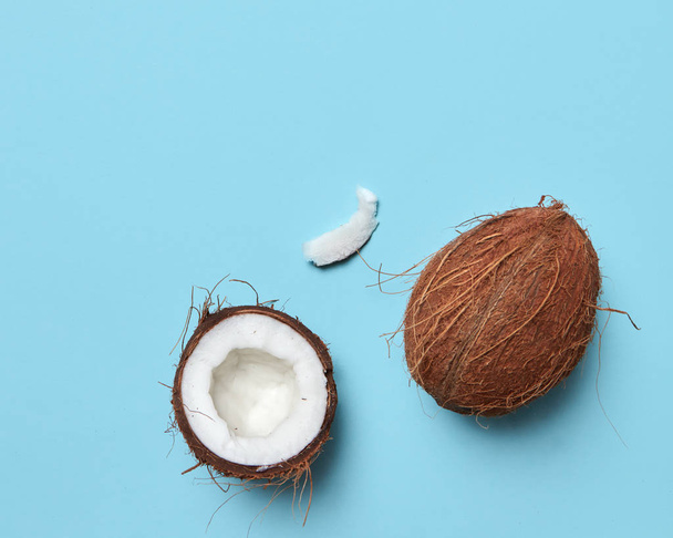 Exotic nut. Whole and half coconut on a blue background with copy space for text. Flat lay - Photo, image