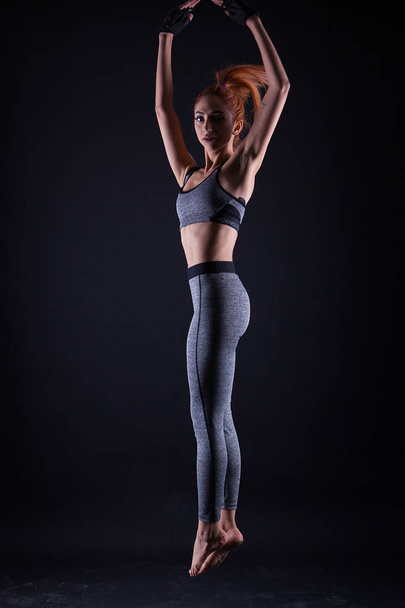 Chica de fitness haciendo salto pose mientras shes en un estudio de sesión de fotos
. - Foto, imagen