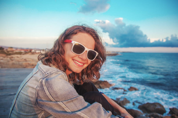 Mooie gelukkig jonge vrouw op badplaats met zonnebril lachen in de stralen van de zon - Foto, afbeelding