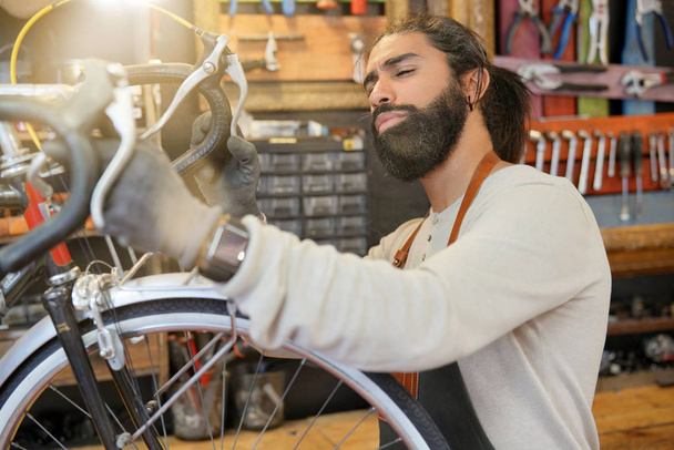 Man working in cycle repair shop - Fotó, kép