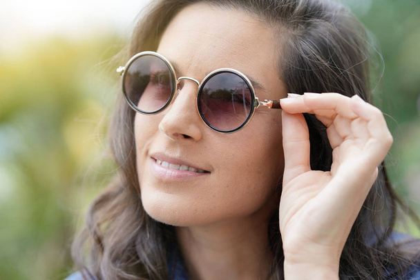 Portrait of smiling brunette woman wearing sunglasses - Фото, изображение