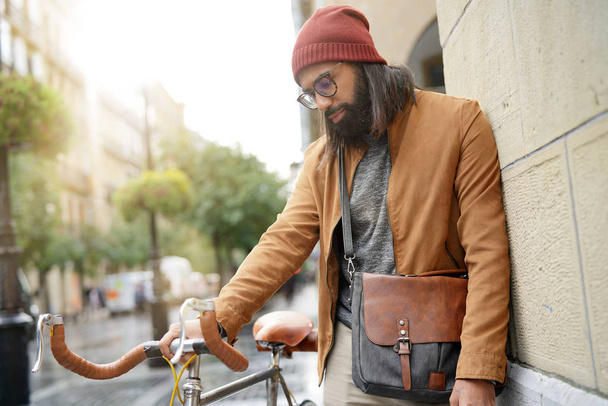 Hipster guy standing with bicycle in the street                       - Foto, imagen