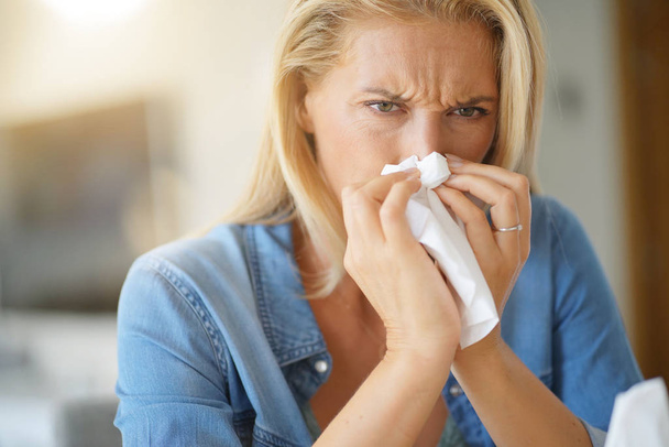 Middle-aged woman with allergy blowing her nose - Foto, imagen