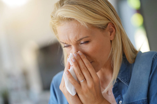 Middle-aged woman with allergy blowing her nose - Фото, зображення