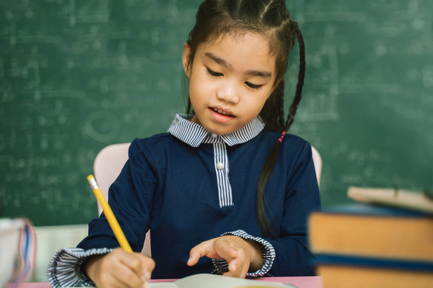 Азиатский ученик начальной школы изучает домашнее задание в классе
. - Фото, изображение