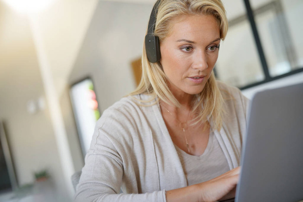 Businesswoman working from home-office, using headset - Foto, afbeelding
