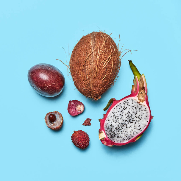 Healthy tropical ripe fruit coconut, passion fruit, lychee, pitahaya on a blue background with space for text. Flat lay. - 写真・画像