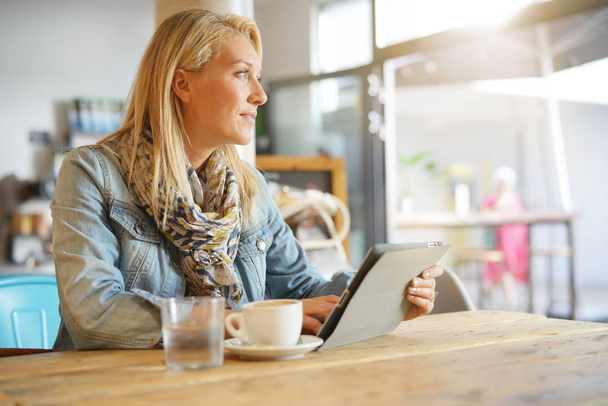 Woman at coffee shop websurfing on digital tablet - Фото, зображення