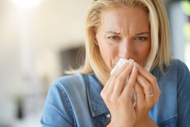 Donna di mezza età con allergia che si soffia il naso
 - Foto, immagini