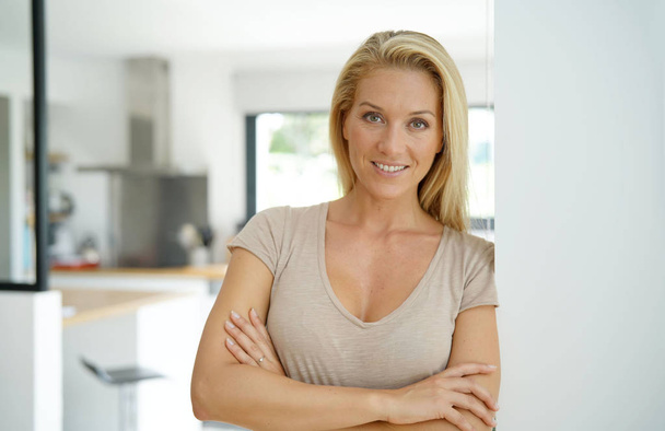 40-year-old blond woman standing inside house - Foto, imagen