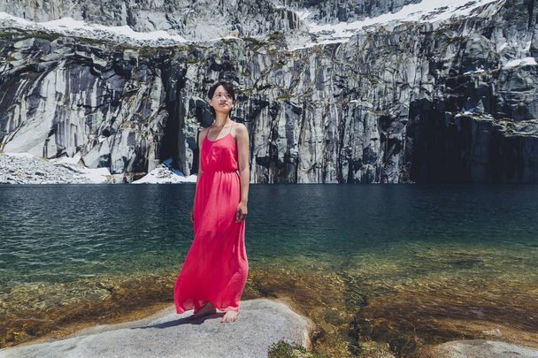 Asian woman with short hair and pink dress poses in the mountains - Photo, Image