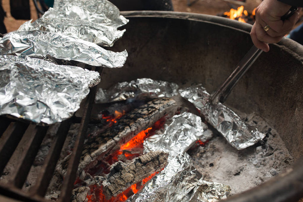 Camping meals prepared in foil cook over a campfire - Photo, Image