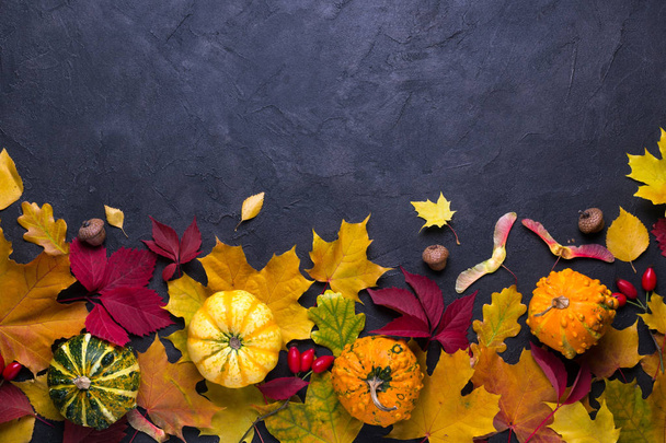 Autumn composition. Frame made of different multicolor dried leaves and pumpkin on dark background. Autumn, fall concept. Flat lay, top view, copy space - Foto, Bild