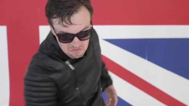 Lindo hombre con gafas de sol en cuero chaqueta de moto baila activamente en la cámara
 - Metraje, vídeo