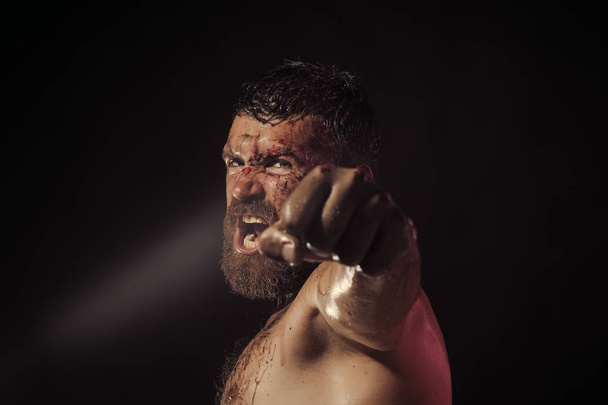 Bearded man show bloody fist on black background - Photo, image