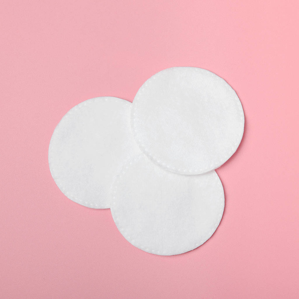 Varias almohadillas de algodón para eliminar el maquillaje sobre un fondo rosa. Cuidado con la cara. Vista superior, plano
 - Foto, Imagen