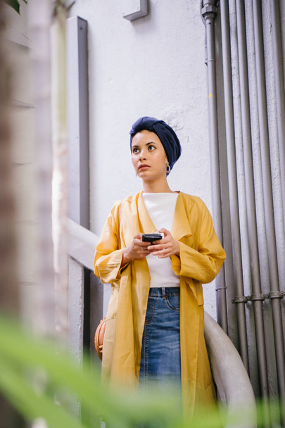 Young and attractive Malay Muslim woman holding smartphone in hands  - Foto, Imagem