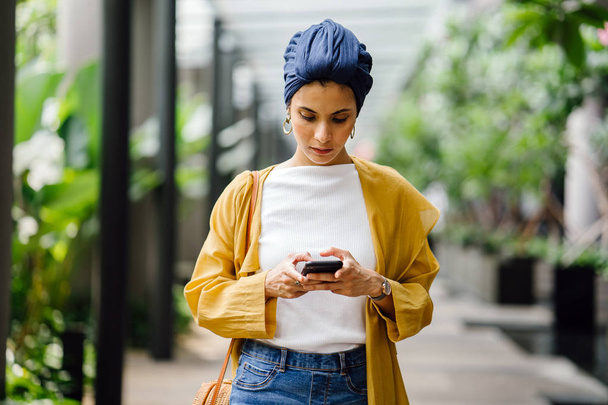 Young and attractive Malay Muslim woman holding smartphone in hands  - Photo, Image