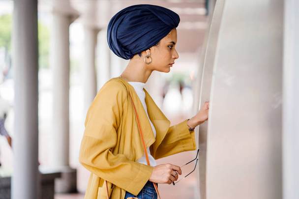Fashion portrait of a tall, slim, young and attractive Malay Muslim woman wearing fashionable clothing and a turban - Foto, imagen
