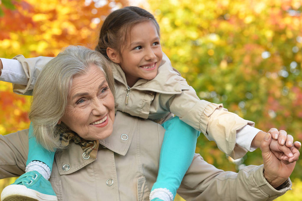 portrait of happy grandmother and granddaughter posing outdoors in autumn  - Photo, Image