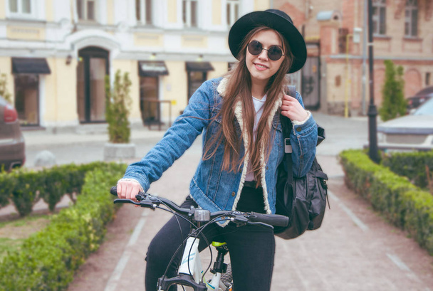 Beautiful european girl riding a bicycle on a city background - Фото, зображення