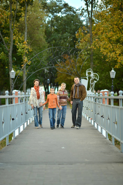Family of four posing on bridge  in autumn  - Фото, изображение