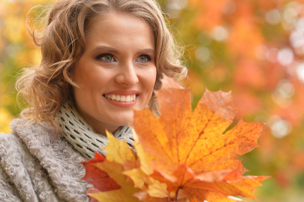 Beautiful young woman holding autumn leaves in park - Valokuva, kuva