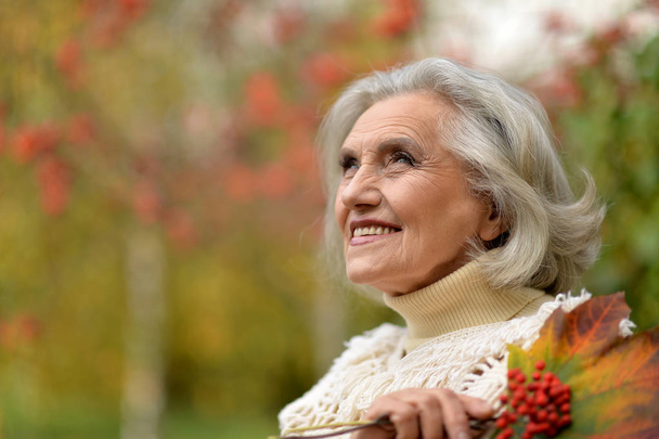 happy  senior beautiful woman with berries in autumnal park - Photo, Image