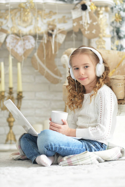 Teenage girl in headphones using laptop while sitting on floor at home - Fotografie, Obrázek