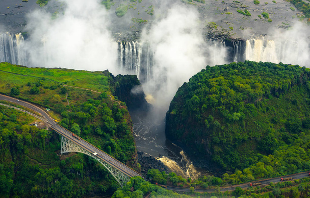 Cataratas Victoria en Zimbabwe y Zambia, Foto helicóptero aéreo, bosque verde alrededor de increíbles cascadas majestuosas de África. Puente Livingston sobre el río
 - Foto, imagen