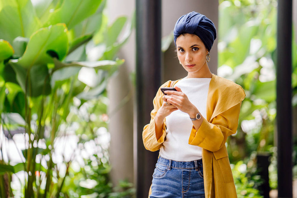 Young and attractive Malay Muslim woman holding smartphone in hands  - Fotoğraf, Görsel