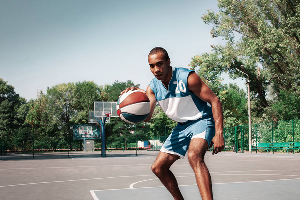 Picture of young confused african basketball player practicing - Foto, Imagen