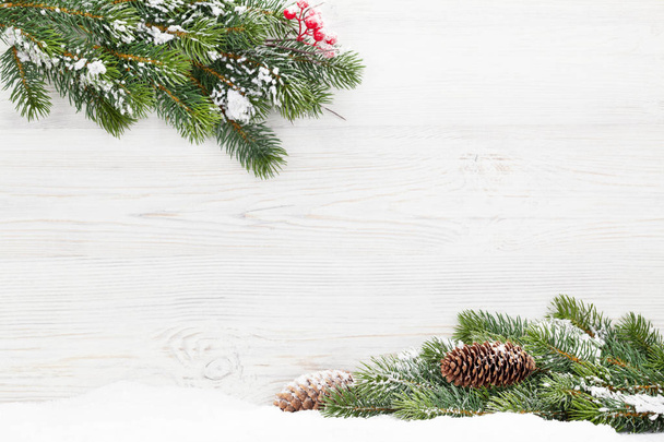 クリスマスのモミの木支店の木製の背景に雪で覆われています。あなたの挨拶のためのスペースとクリスマス カード背景 - 写真・画像