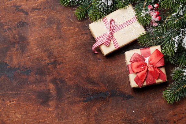Coffrets cadeaux de Noël et branche de sapin recouverte de neige sur fond bois. Fond de Noël vue de dessus avec de l'espace pour vos salutations
 - Photo, image