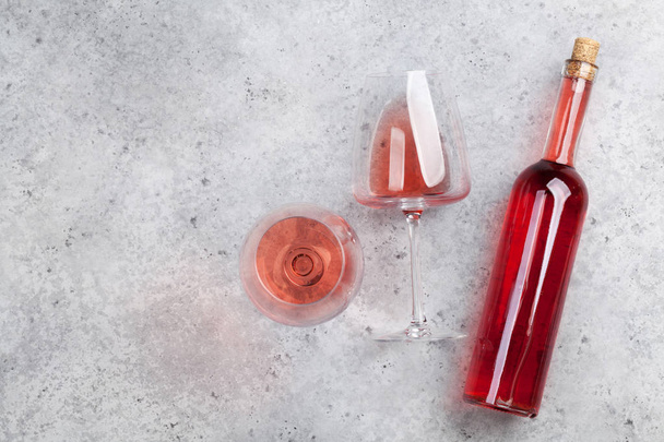 Бутылка с розовым вином и стакан лежат на каменном фоне. Вид сверху с пространством для вашего текста
 - Фото, изображение