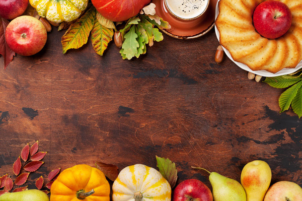Autumn backdrop with pumpkins, apple, coffee, cake and colorful leaves on wooden background. Top view with space for your text - Foto, Imagem