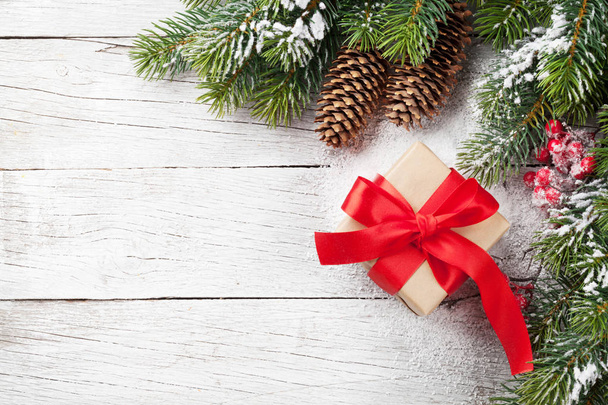 Geschenk box en sneeuw fir kerstboom op houten tafel. Bovenaanzicht met ruimte voor uw groeten - Foto, afbeelding