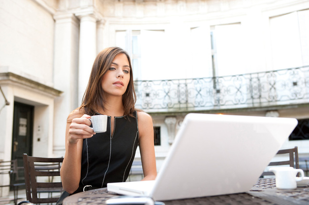 Young attractive businesswoman sitting in a luxurious coffee shop terrace with her laptop - Photo, Image