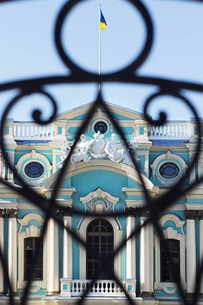Фрагмент фасада Мариинского дворца с украинским флагом на крыше, вид через кованый забор, Киев, Украина
 - Фото, изображение