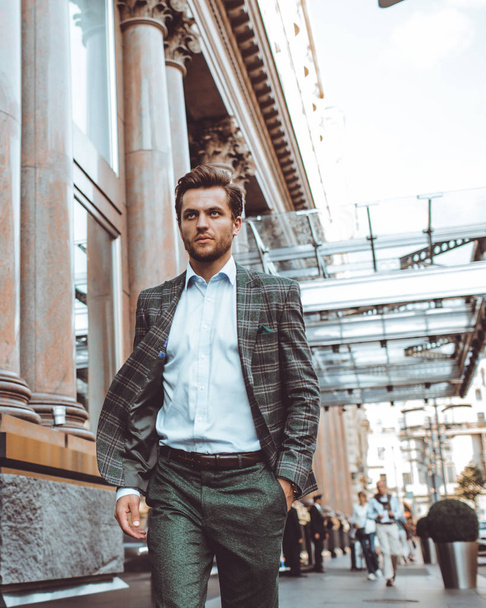 serious elegant Caucasian gentleman in tweed suit jacket walking in street at building  - Photo, Image