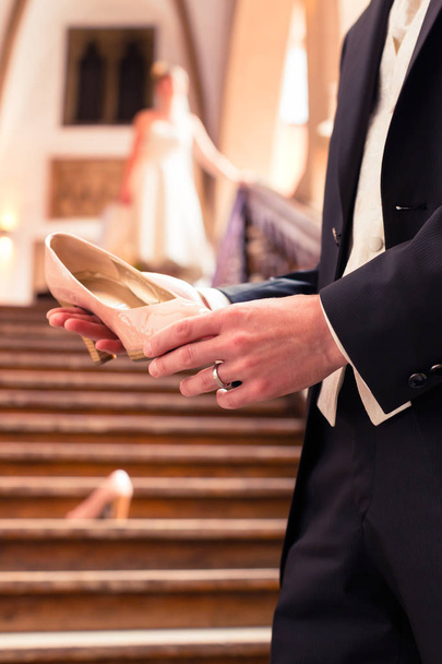 Bridegrooms hand holding brides wedding shoe - Fotoğraf, Görsel