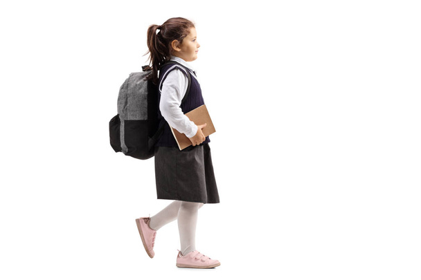 Female pupil with backpack holding book and walking isolated on white background - Fotografie, Obrázek
