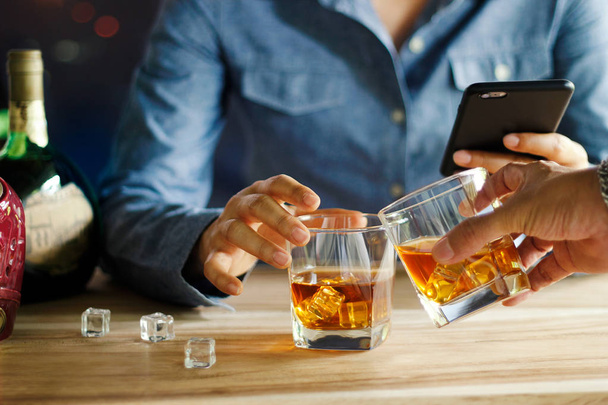 クローズ アップ 2 男性のパブでカウンター バーでウイスキー グラスのアルコール飲料を擦れる - 写真・画像